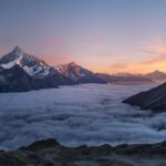 Snow pyramid of a Tianshan giant rising above a sea of clouds at golden hour