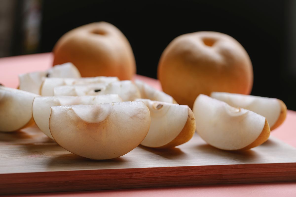 Sliced Asian pear showing crisp white flesh on a wooden board