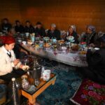 Uyghur family sharing tea and a table of dishes, Xinjiang