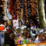 Colorful bazaar stall with hanging copper cups, dried produce, and spices
