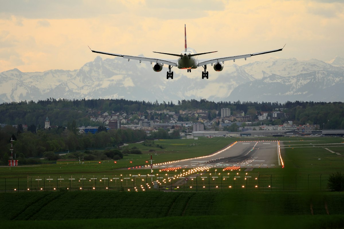 A passenger plane on final approach over snow-capped mountains
